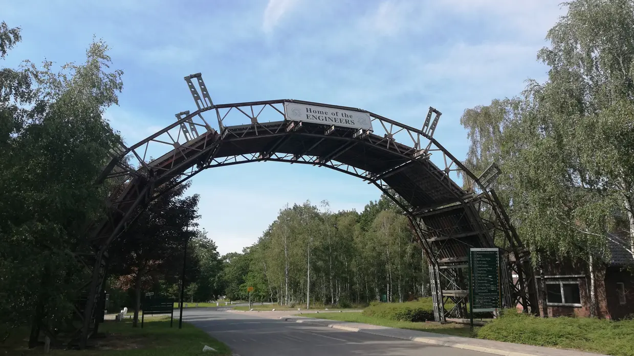 Brug in de vorm van een halve maan over een weg en bord met de tekst 'home of the engineers'.