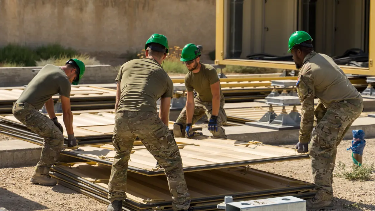 4 militairen tillen samen de wand van een container.