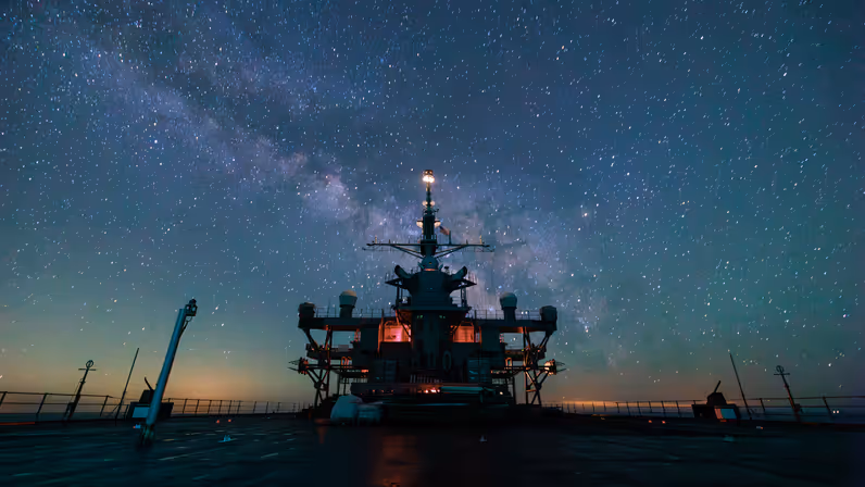 De USS Mount Whitney op zee, met op de achtergrond de Melkweg. 