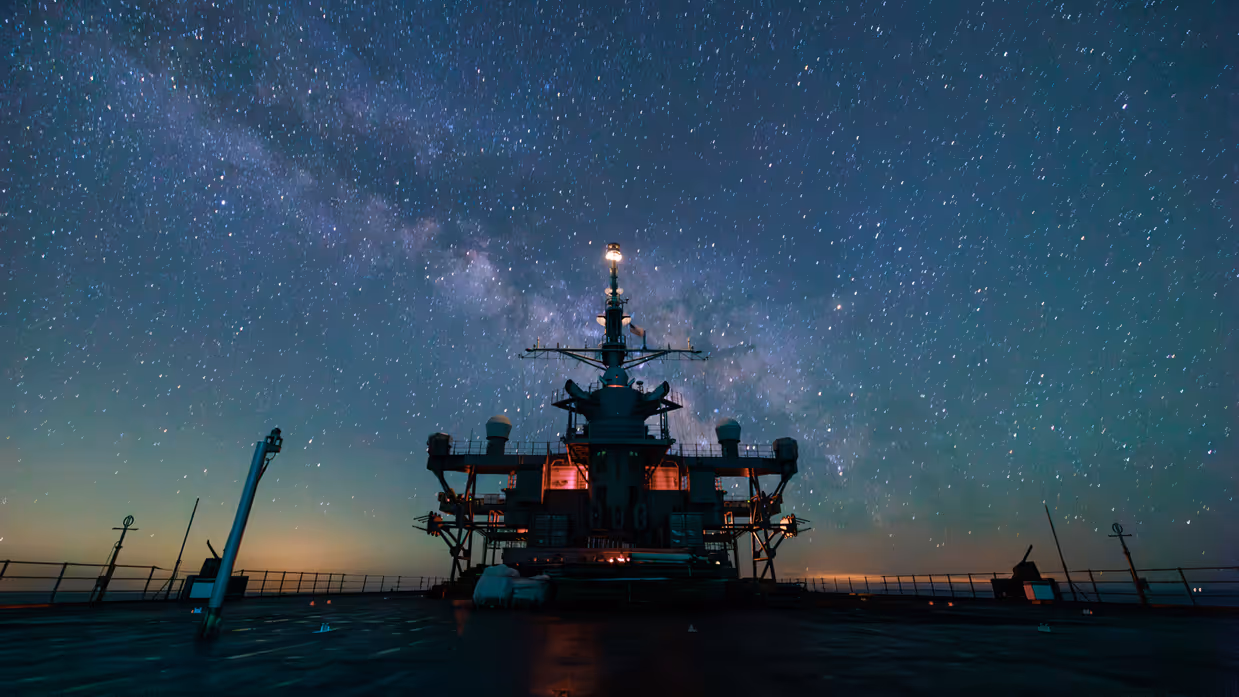 De USS Mount Whitney op zee, met op de achtergrond de Melkweg. 