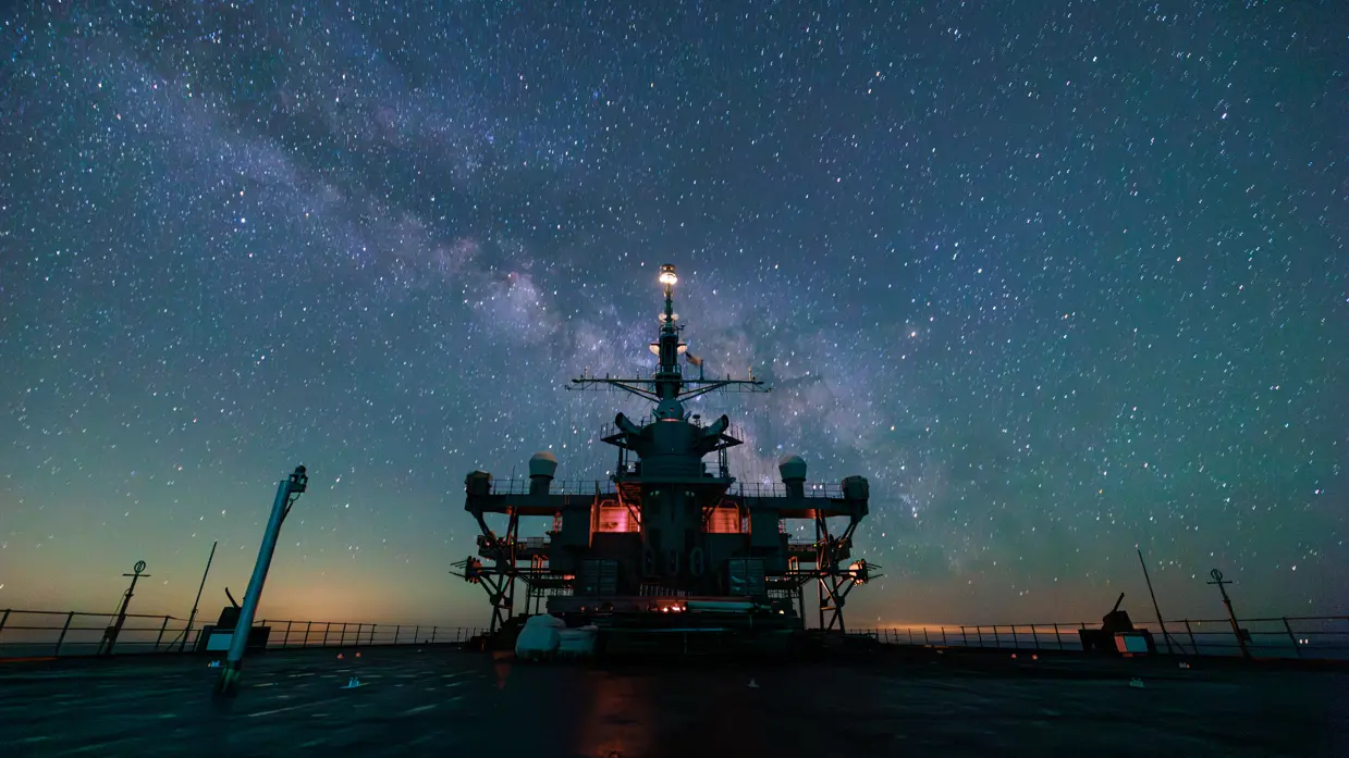 De USS Mount Whitney op zee, met op de achtergrond de Melkweg. 