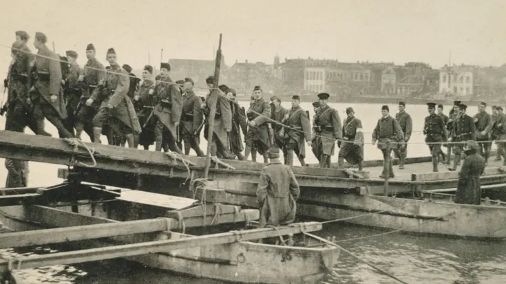 Grote groep militairen lopen over een brug.
