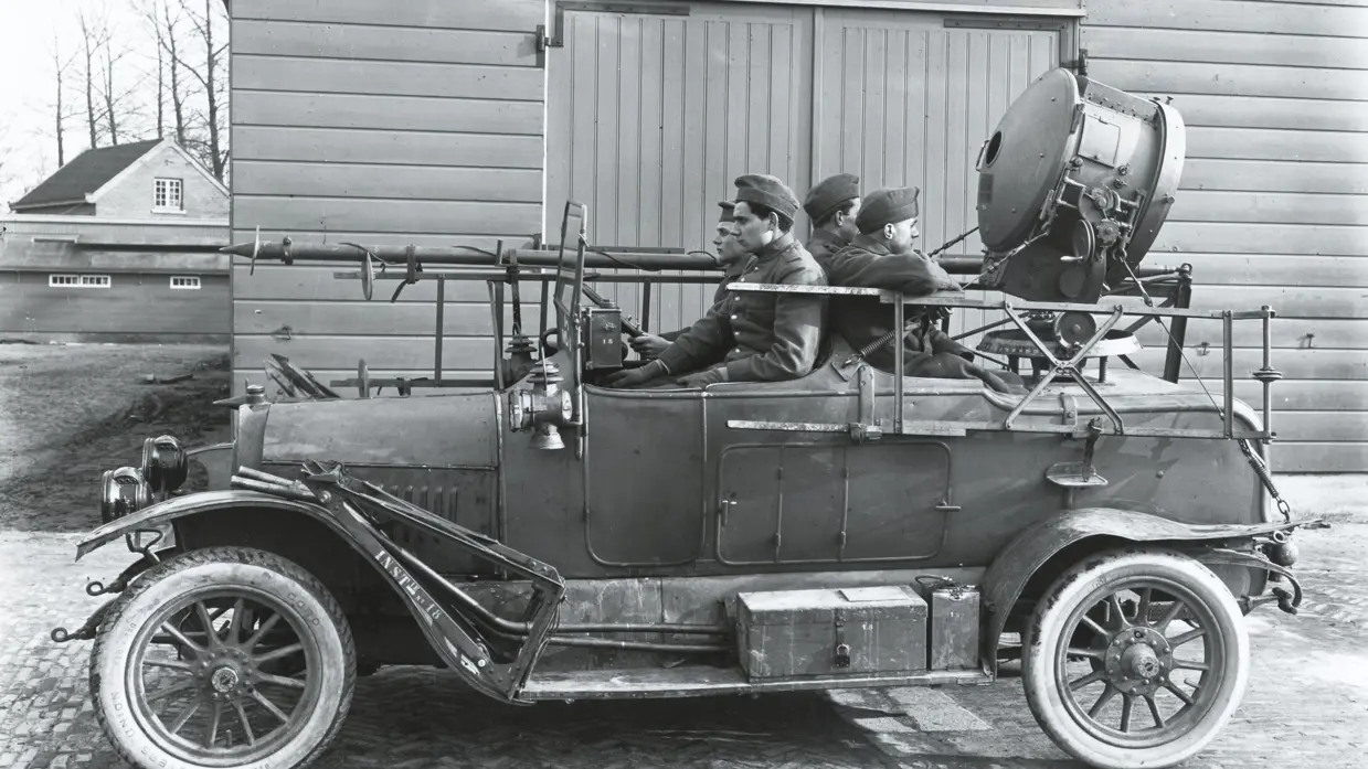 4 militairen zitten in een auto met een zoeklicht.