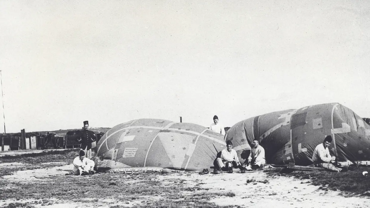 Een aantal militairen zittend op de grond naast een doelballon.