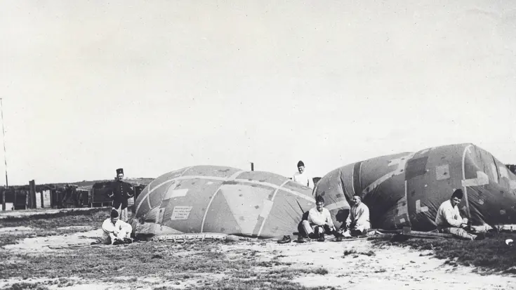 Een aantal militairen zittend op de grond naast een doelballon.