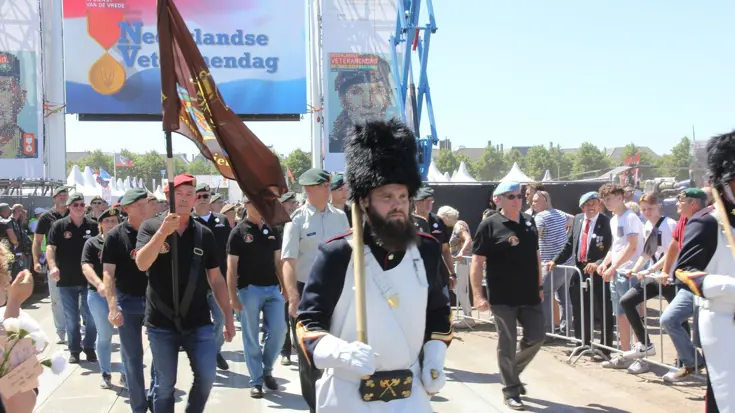 Militairen lopen onder poort door tijdens veteranendag.