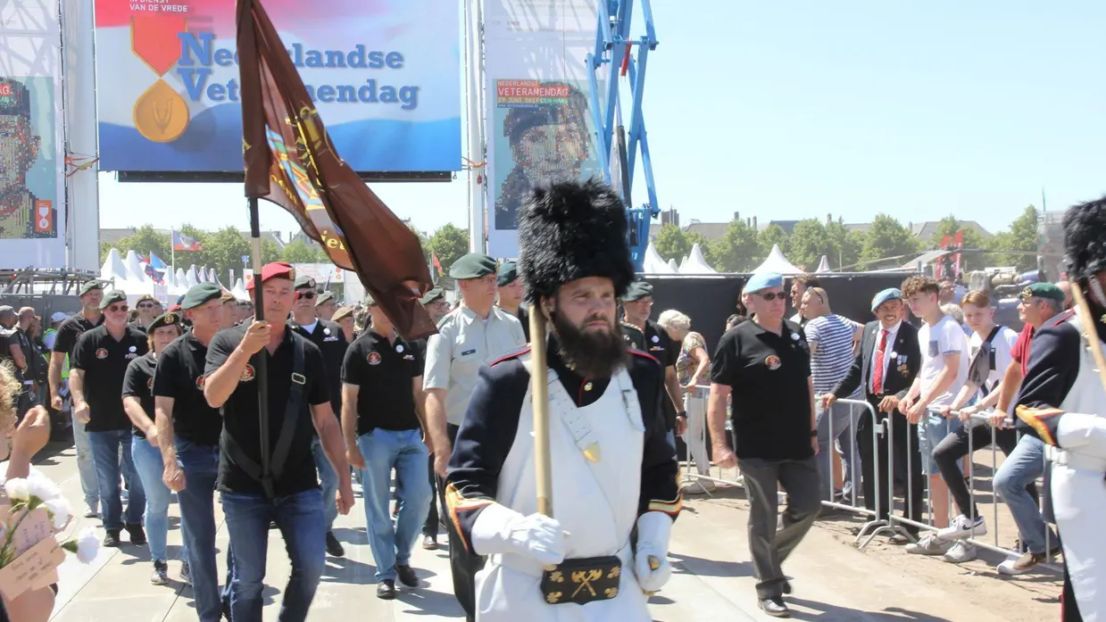 Militairen lopen onder poort door tijdens veteranendag.