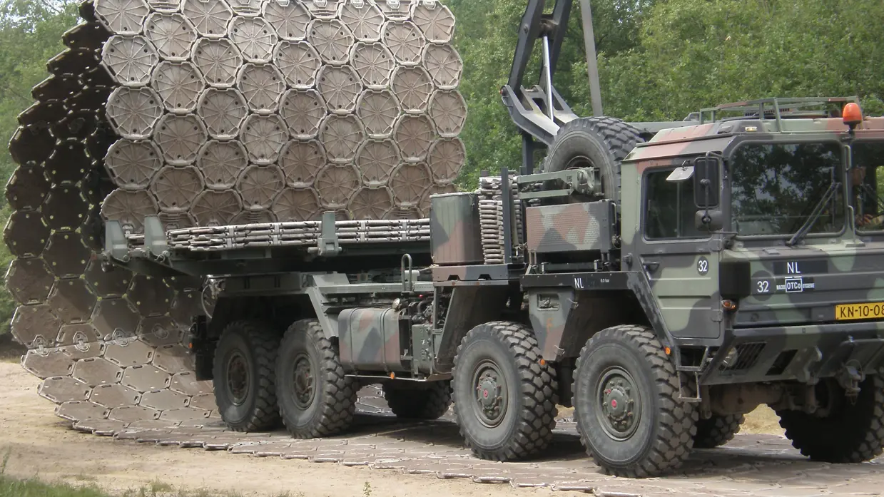 Vrachtwagen plaatst metalen wegenmatsysteem.