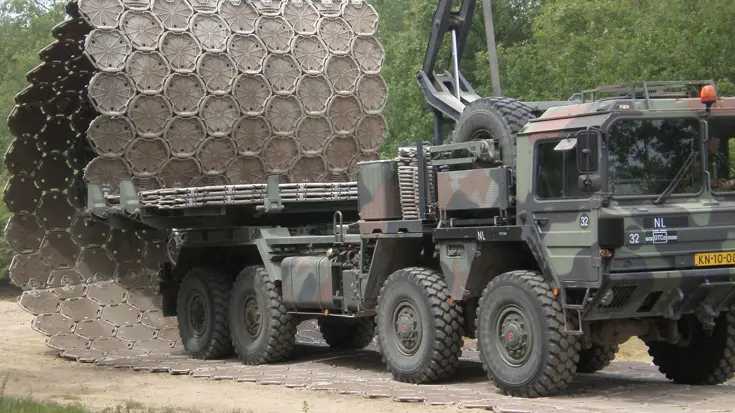 Vrachtwagen plaatst metalen wegenmatsysteem.