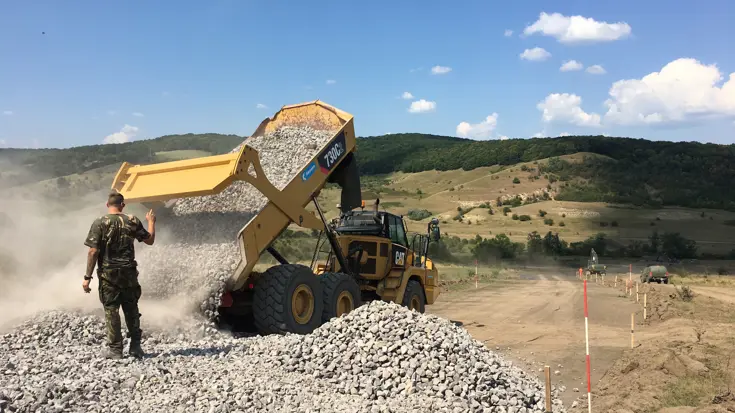 Een kiepauto lost stenen tijdens een oefening in Roemenië.