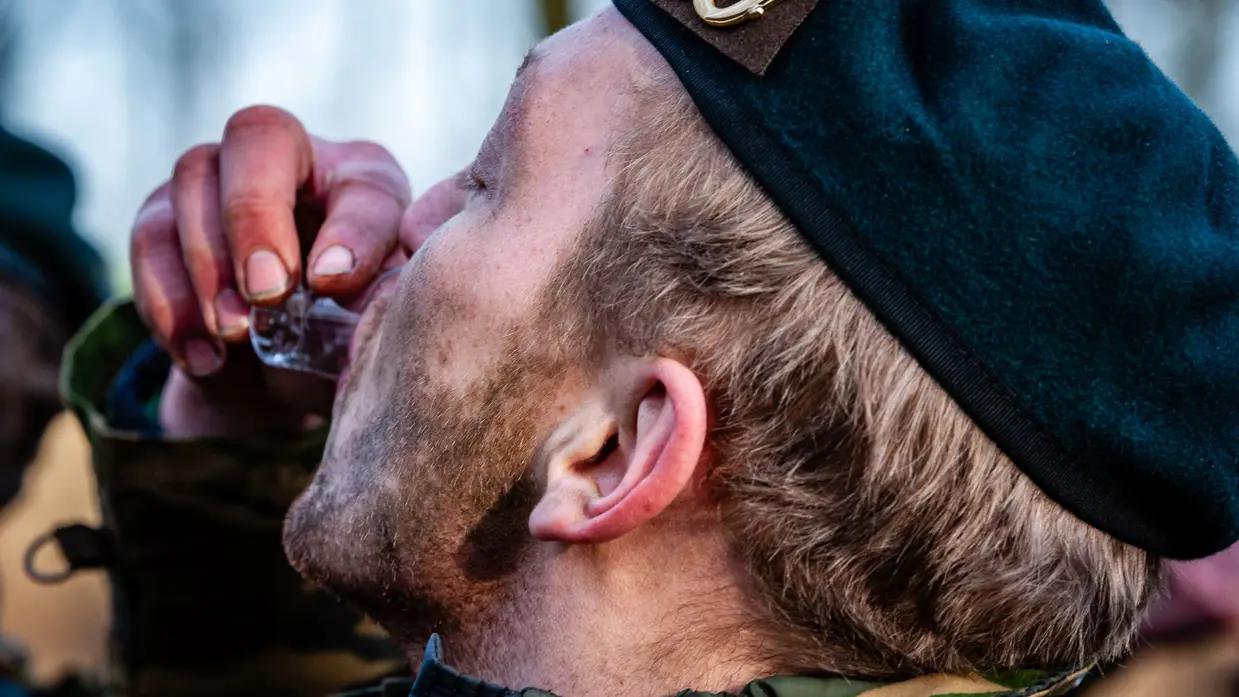 Een militair drink uit een klein glaasje.