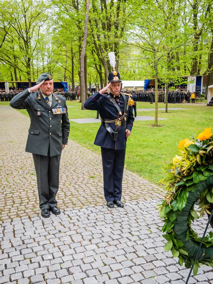 De regimentscommandant en -adjudant salueren voor een krans.