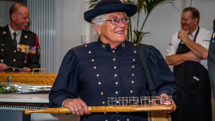 Marketenster houdt een peddel vast met daarop 6 met drank gevulde kleine glaasjes.