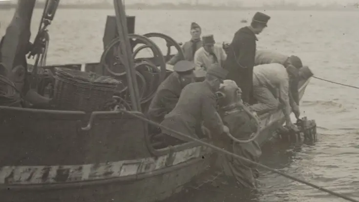 Genieduiker wordt op een boot geholpen op de Merwede, 1920.
