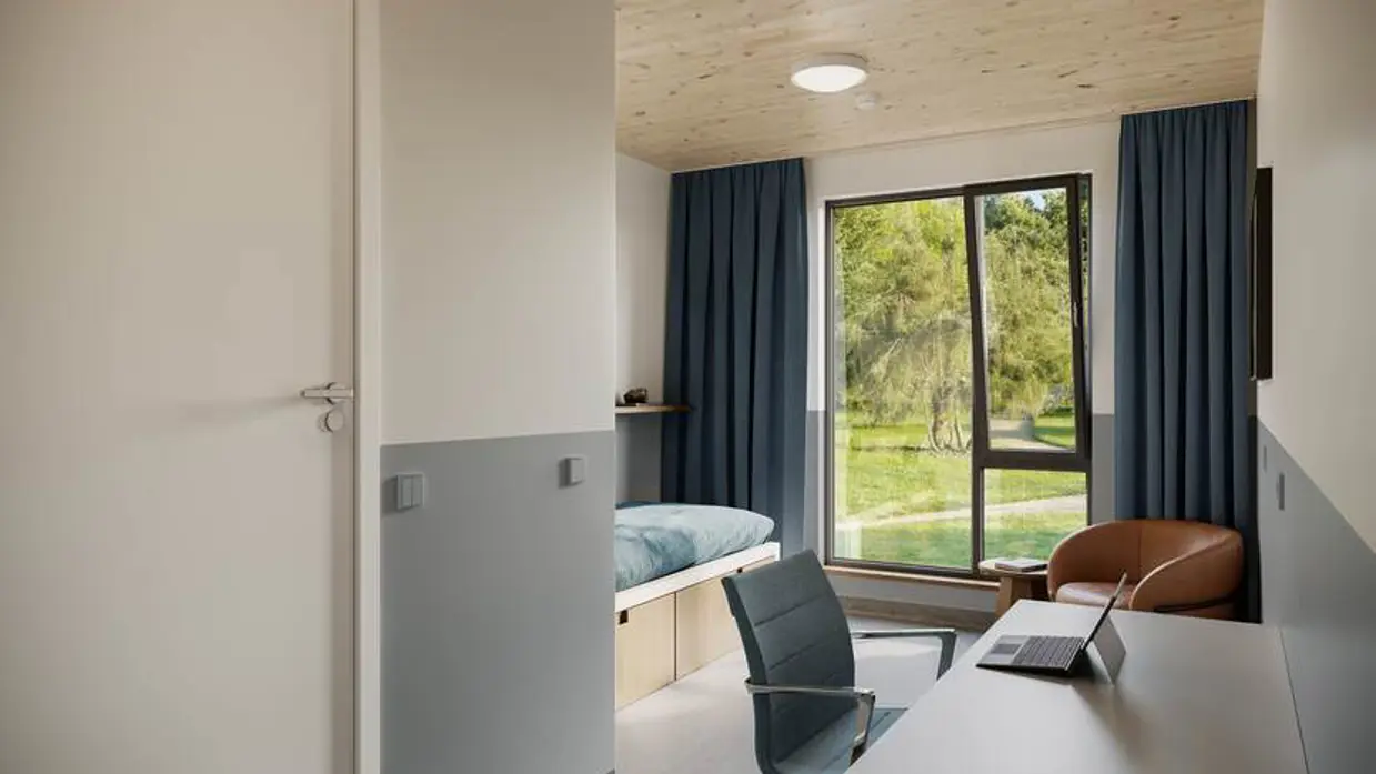 Een eenpersoons slaapkamer met stoel en bureau.