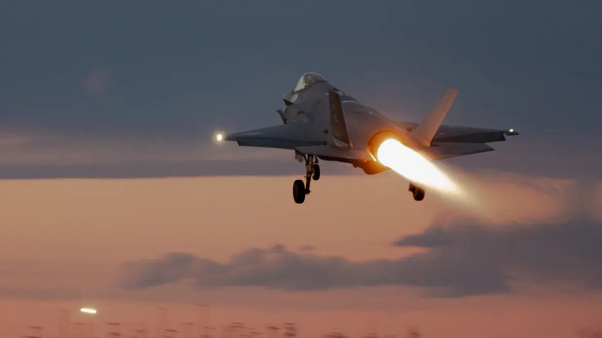 In het donker opstijgende F-35 met zichtbare naverbrander. De lucht is paars-oranje.