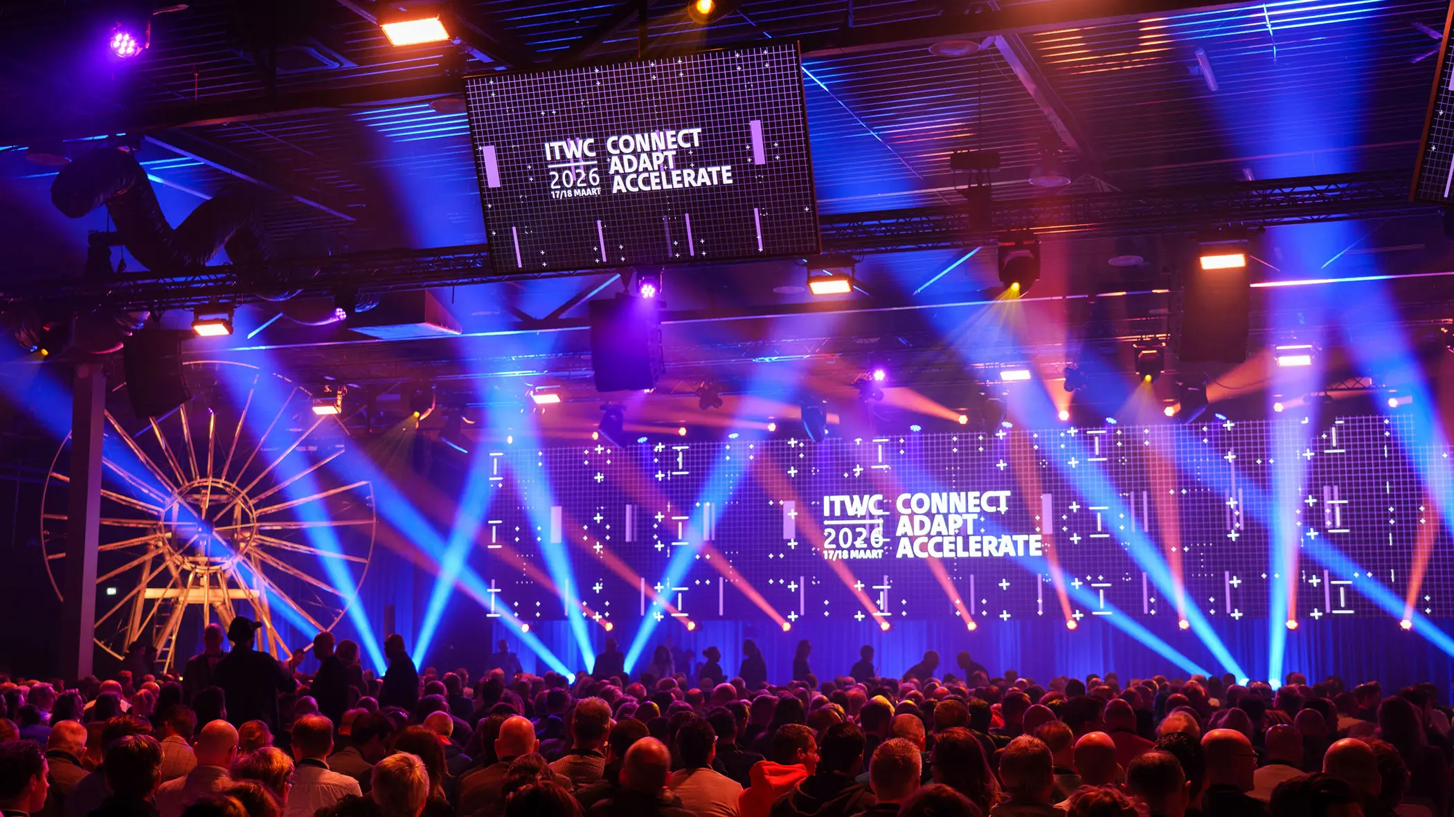 Volle conferentiezaal met lichtshow.