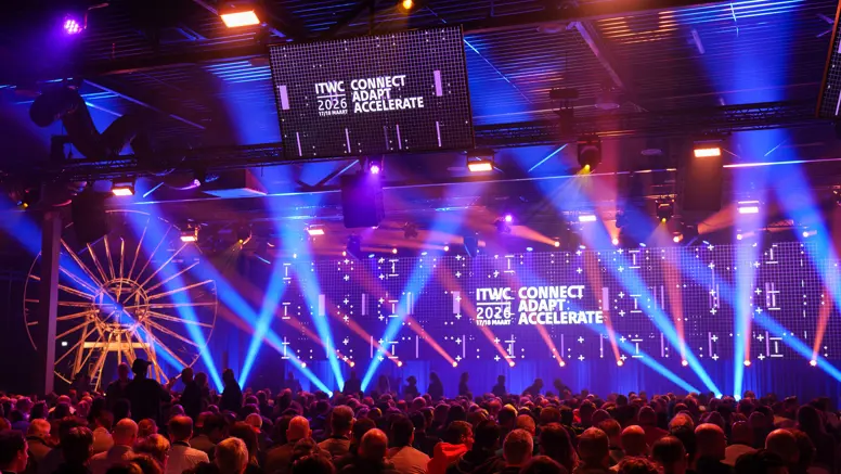 Volle conferentiezaal met lichtshow.