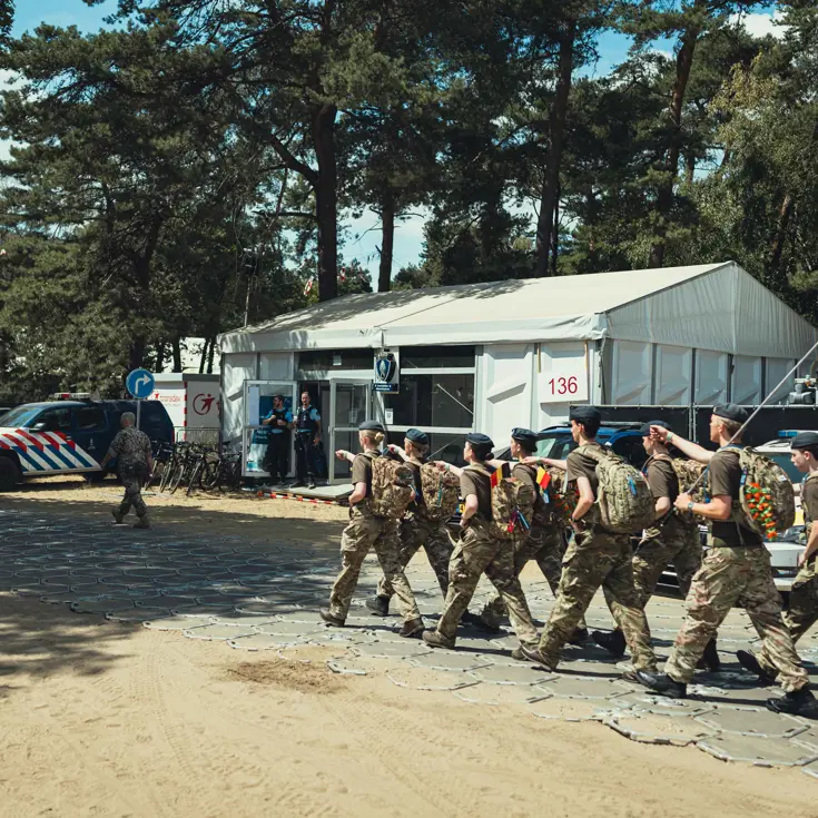 Engelse militairen lopen kamp Heumensoord op, in de verte een voertuig van de Koninklijke Marechaussee.