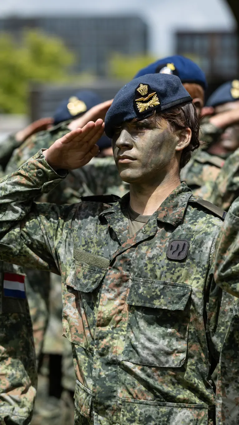 Saluerende militairen met baretten op