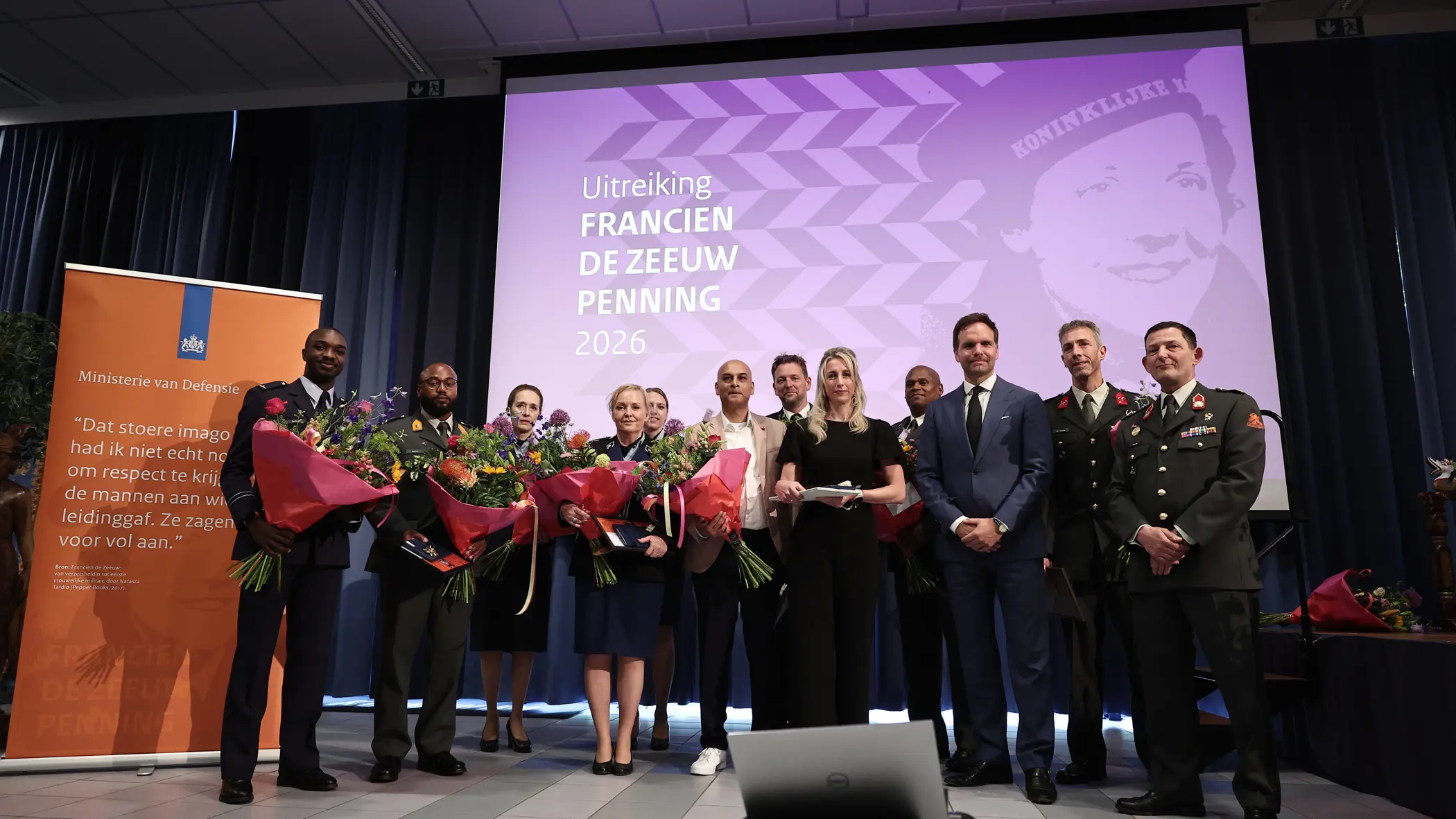 Twaalf personen, van wie het merendeel in militair uniform, poseren naast elkaar met ieder een bos bloemen in de hand.