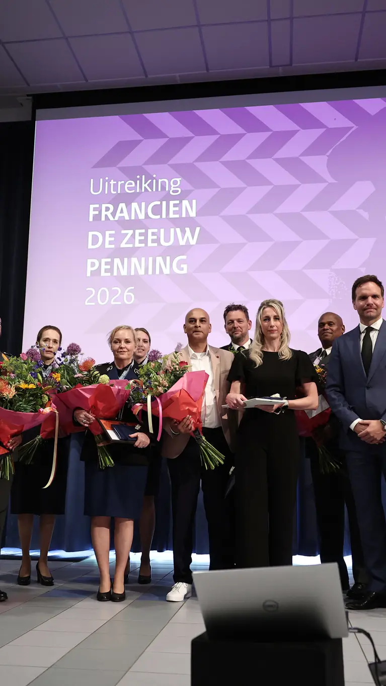Twaalf personen, van wie het merendeel in militair uniform, poseren naast elkaar met ieder een bos bloemen in de hand.