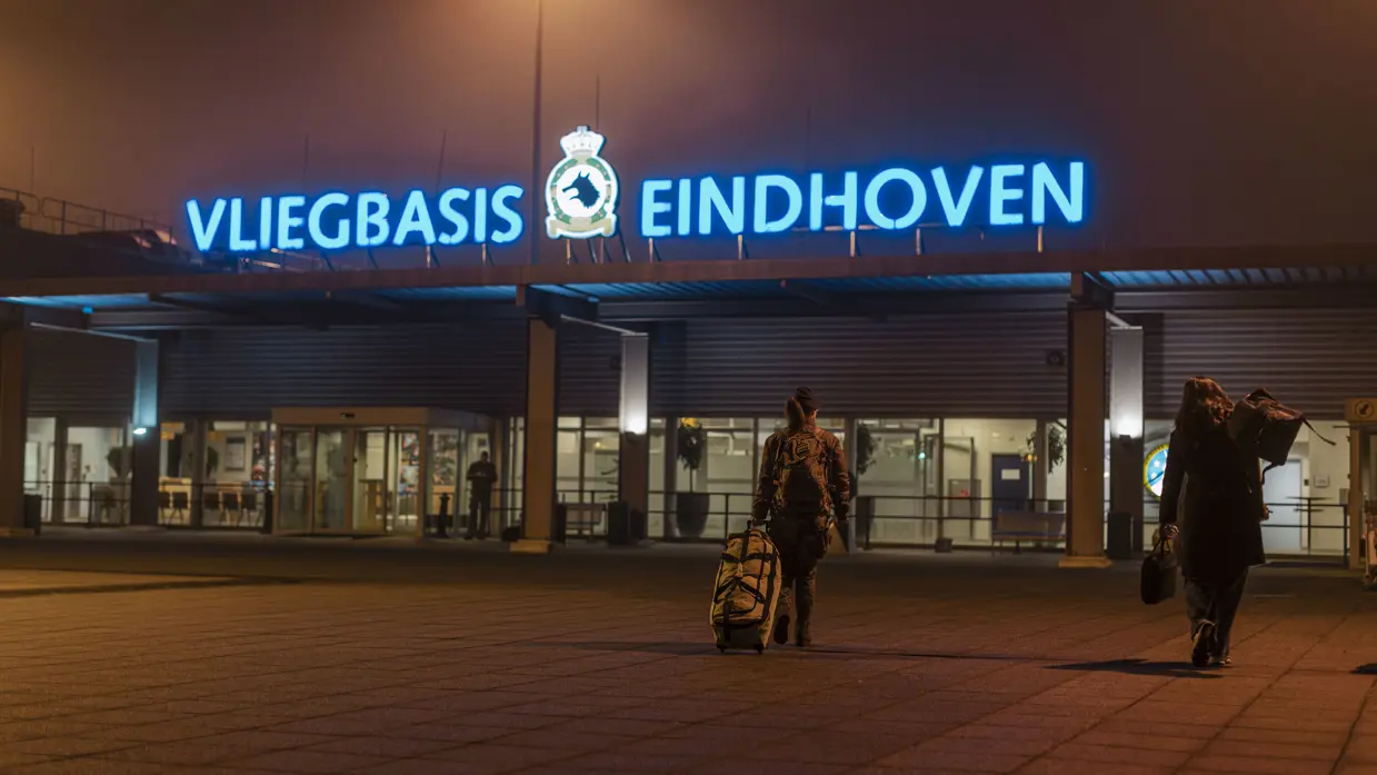 De ingang van Vliegbasis Eindhoven, af te lezen op de grote blauwe neonletters boven het gebouw. Daarnaast een vliegende C-390M.