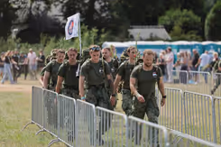 Militairen wandelen tussen dranghekken op grasveld.