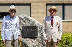 Twee veteranen poseren naast een monument.
