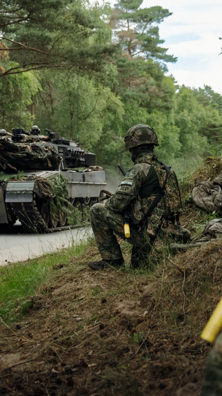 Marechaussees van 103 Marechaussee Eskadron met op de achtergrond een voertuig van de Landmacht.