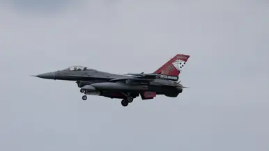 Een F-16 in de landing onder een blauwe lucht. 