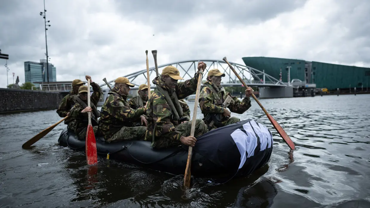 De deelnemers aan de NWT roeien in rubberboten door Amsterdam.