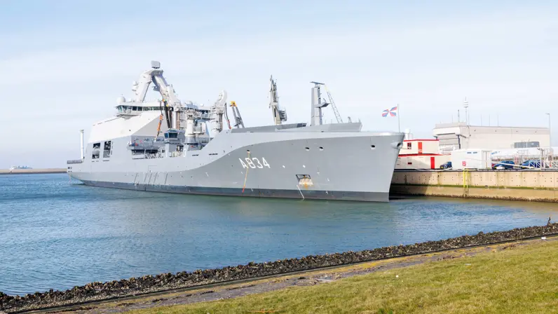 Het grijze marineschip ligt aan de kade.