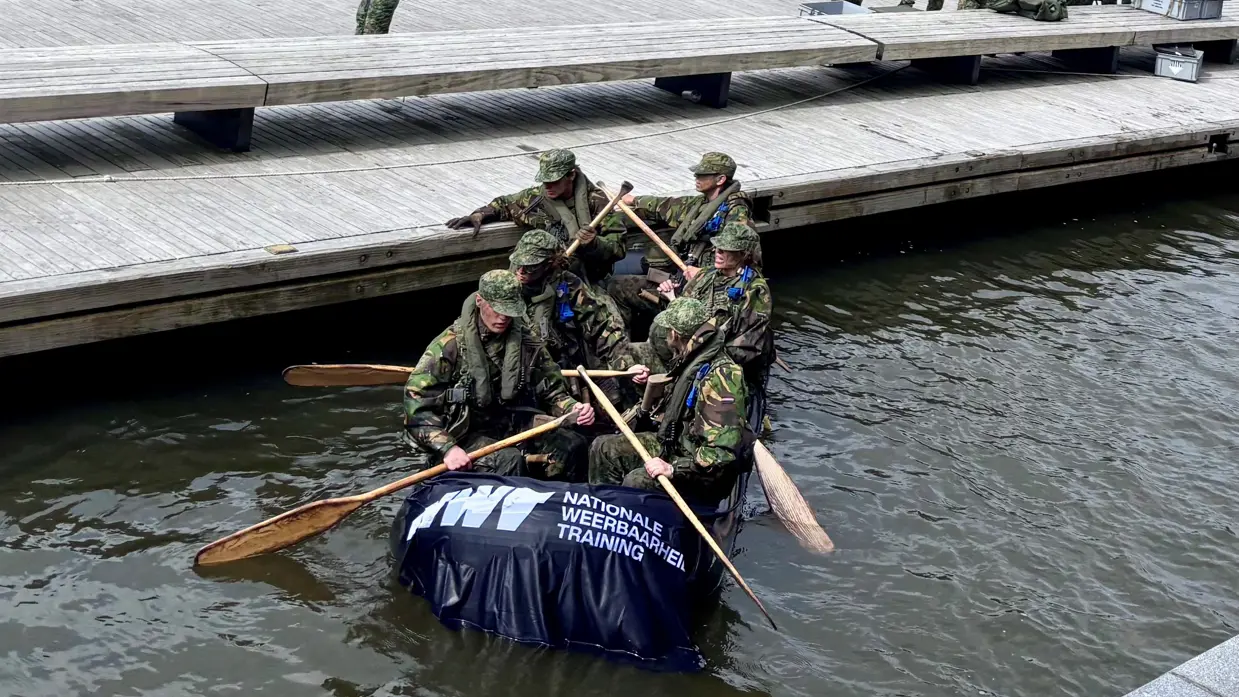 De deelnemers aan de NWT roeien in rubberboten door Amsterdam.