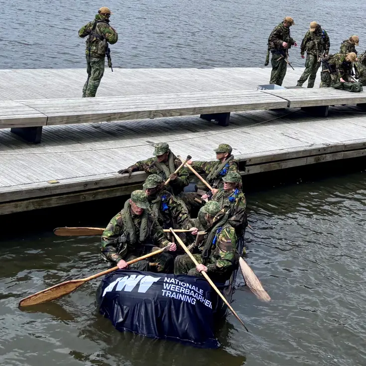 De deelnemers aan de NWT roeien in rubberboten door Amsterdam.