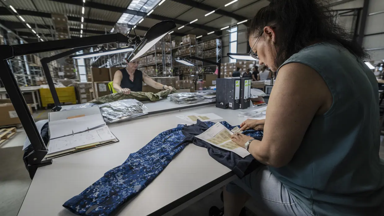 Twee vrouwen werken aan een tafel aan militaire kledingstukken.