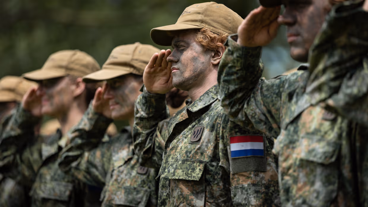 Saluerende militairen met petten op. 