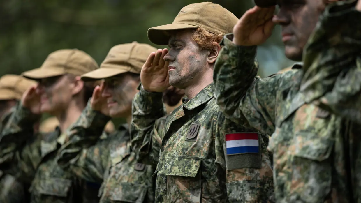 Saluerende militairen met petten op. 
