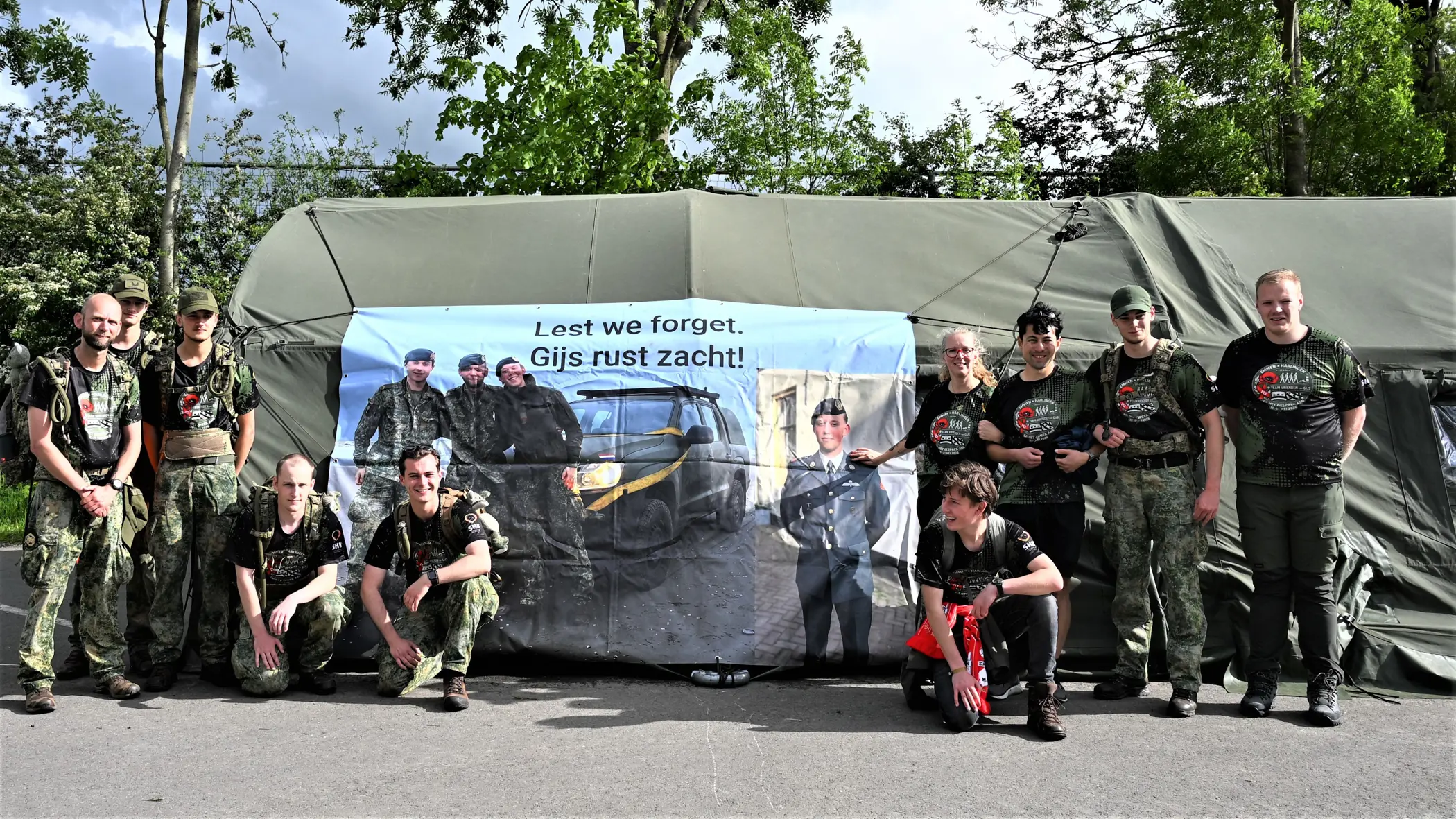 De lopers voor een groene tent waar een banner aan hangt.  