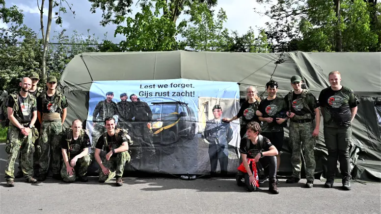 De lopers voor een groene tent waar een banner aan hangt.  
