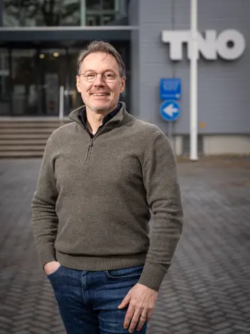 Portretfoto van Rajko Brokken. Vaag op de achtergrond is de afkorting TNO te zien.