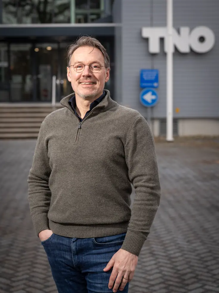Portretfoto van Rajko Brokken. Vaag op de achtergrond is de afkorting TNO te zien.