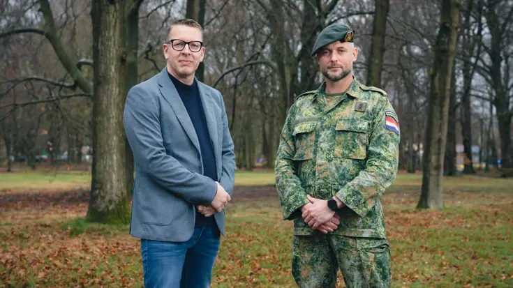 Portretfoto van projectleider Michel en majoor Jean. De twee staan naast elkaar en hebben hun handen voor zich. Daarachter een bosrijke omgeving.