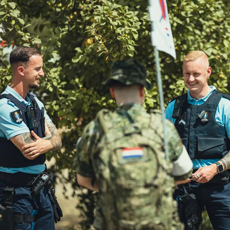 Twee Marechaussees in gesprek met een militair in groen tenue tijdens de Nijmeegse 4Daagse.