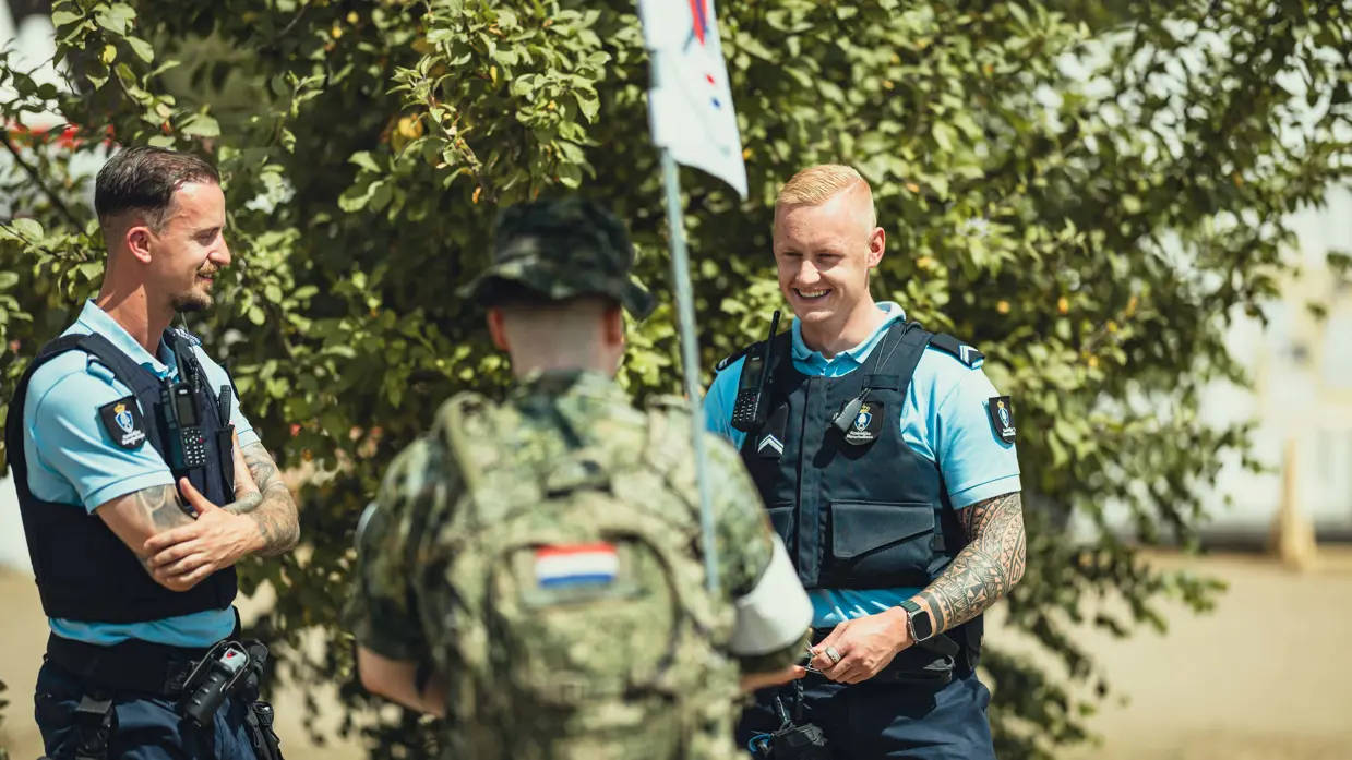 Twee Marechaussees in gesprek met een militair in groen tenue tijdens de Nijmeegse 4Daagse.