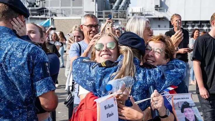 Een marinevrouw omhelst haar familieleden bij terugkeer op de kade.