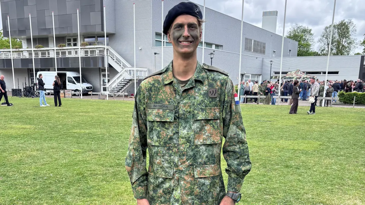 Een militair staat op een grasveld. 