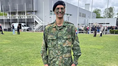 Een militair staat op een grasveld. 
