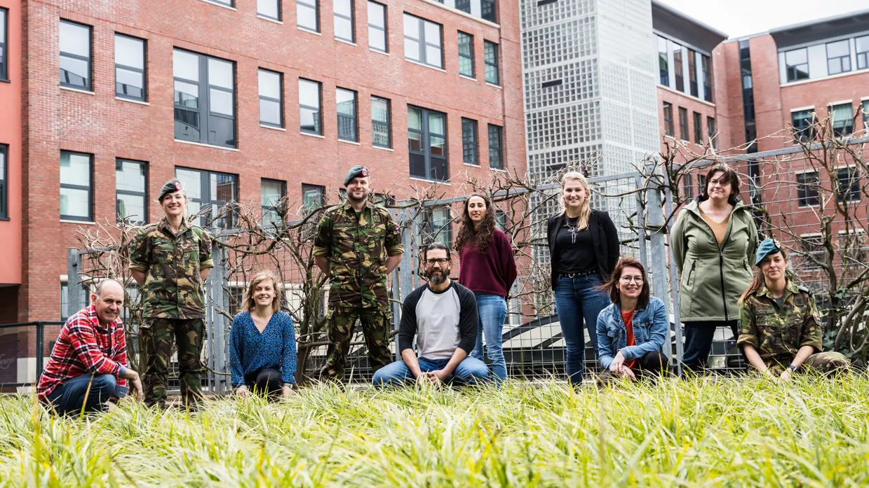 Een groep mensen poseren voor de foto met als achtergrond een gebouw.
