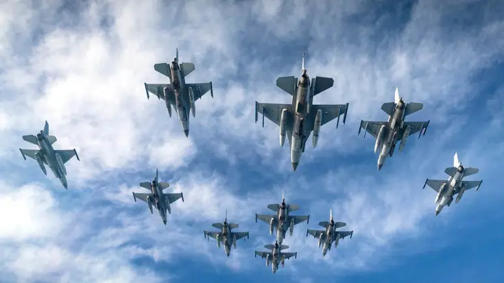 10 Nederlandse F-16's van onderaf gezien terwijl ze in formatie vliegen.